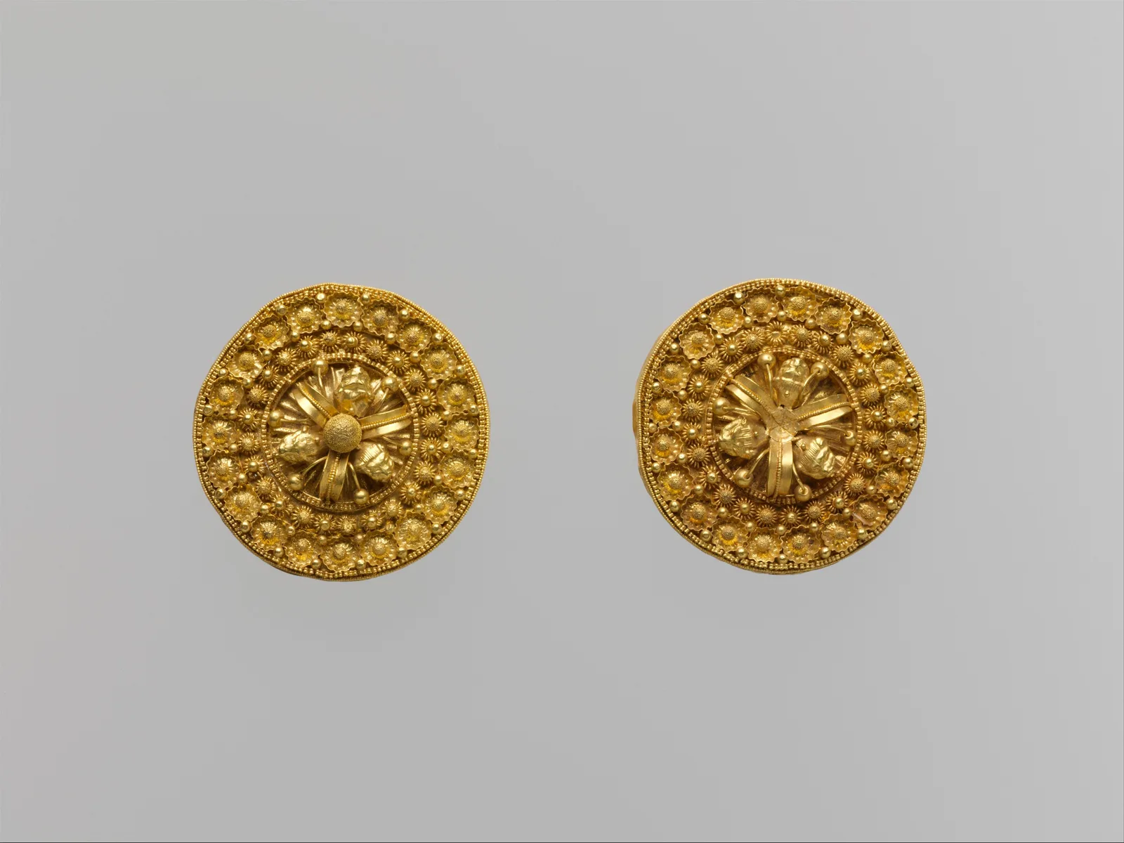 Pair of Etruscan gold disks with a four-petal flower at each center and a field of tiny rosettes
