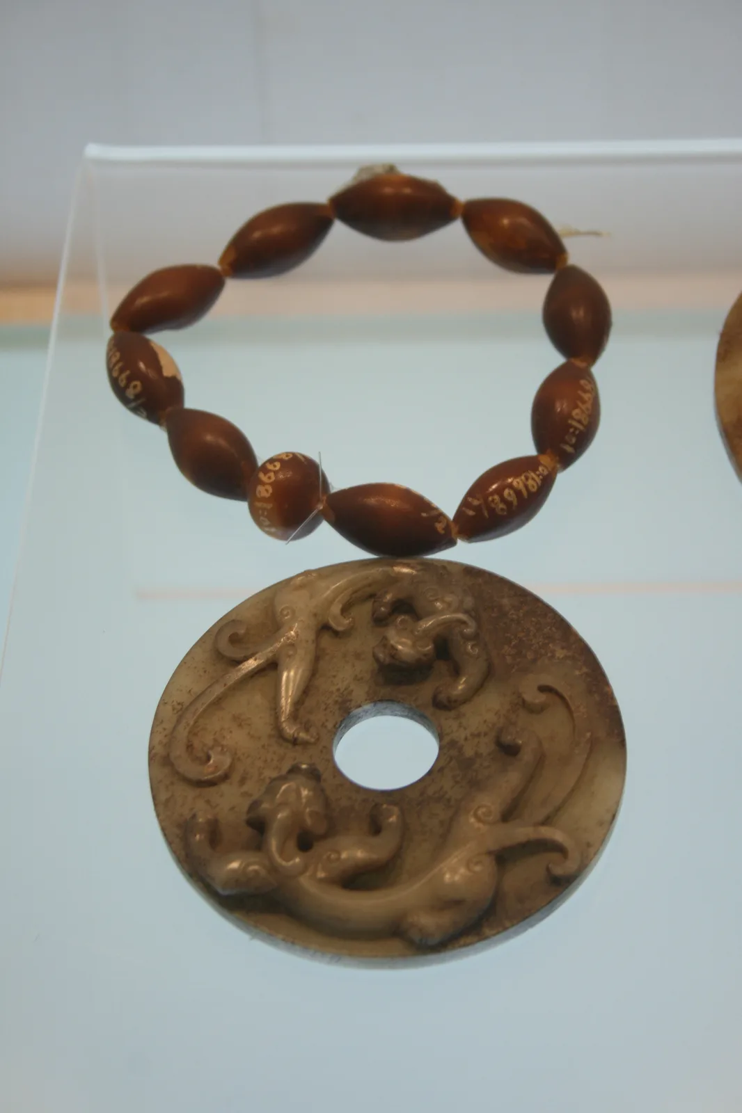 Song-dynasty amber necklace of honey-colored beads, a jade disc resting beside the strand