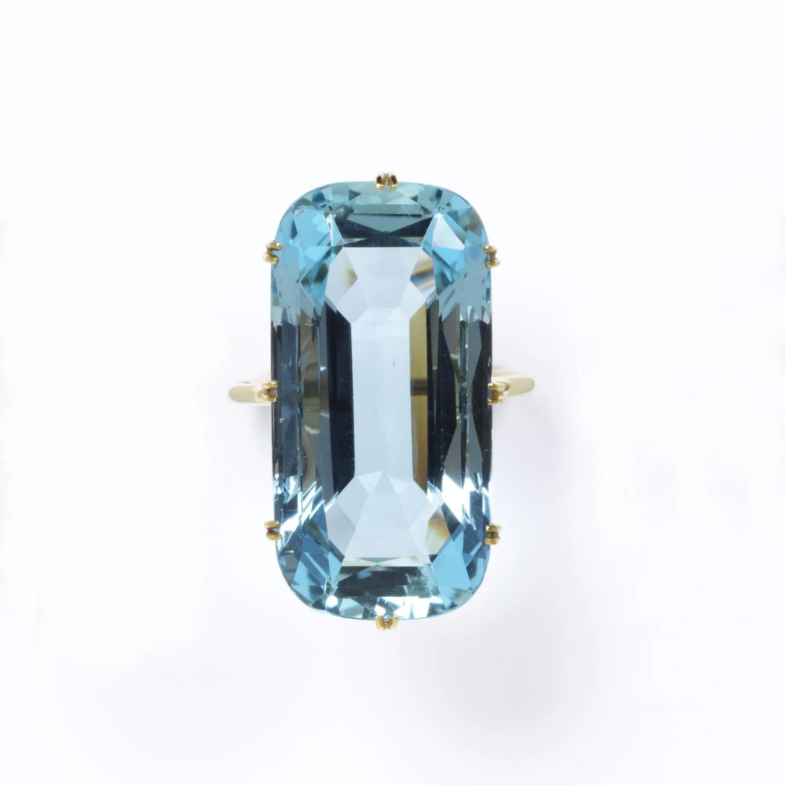 A long oblong faceted pale-blue aquamarine set in a slim gold coronet mount, the stone already a transparent water pane
