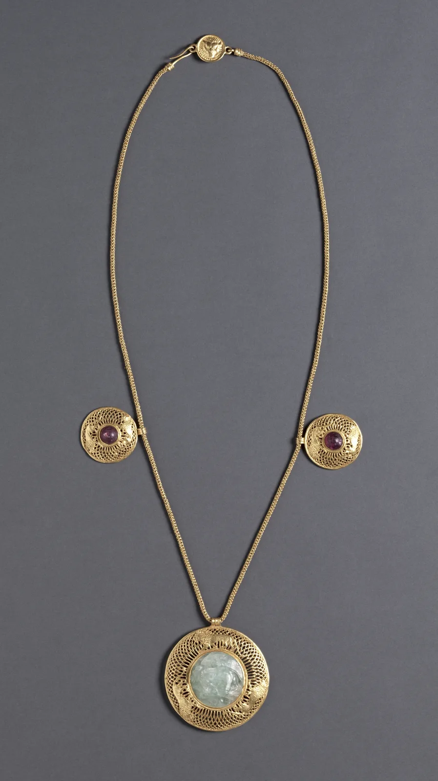 Roman gold necklace with a large circular openwork pendant holding a pale watery beryl disk, two smaller gold disks with amethysts on the chain