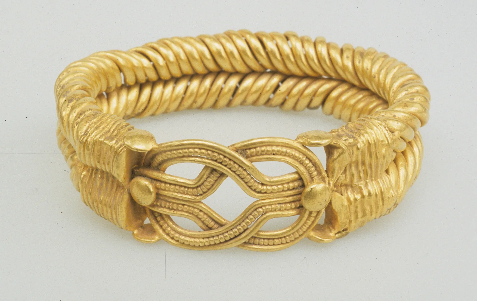 Roman-period gold bracelet of two spirally twisted strands meeting at a Herakles knot with granulated loops and gold bosses