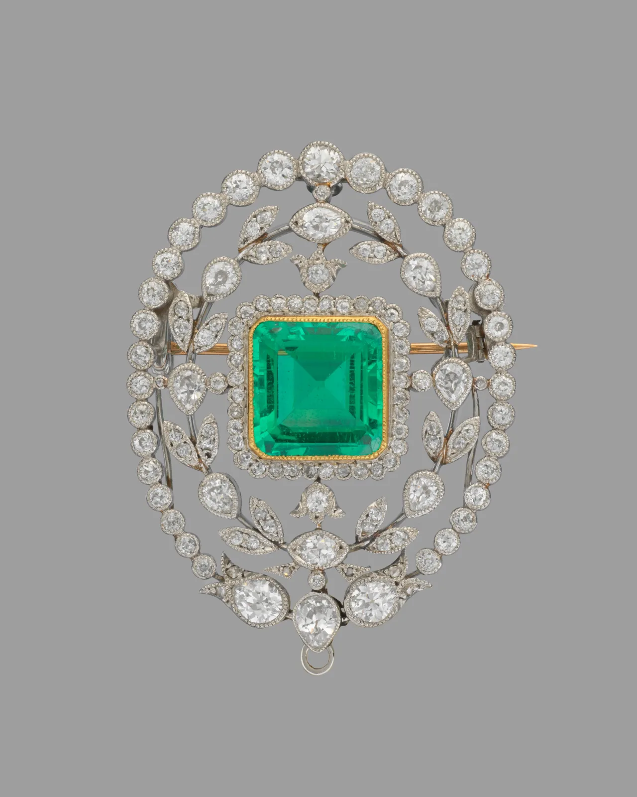 Tiffany platinum and gold brooch with a large rectangular step-cut emerald in a diamond wreath, the emerald’s corners clipped