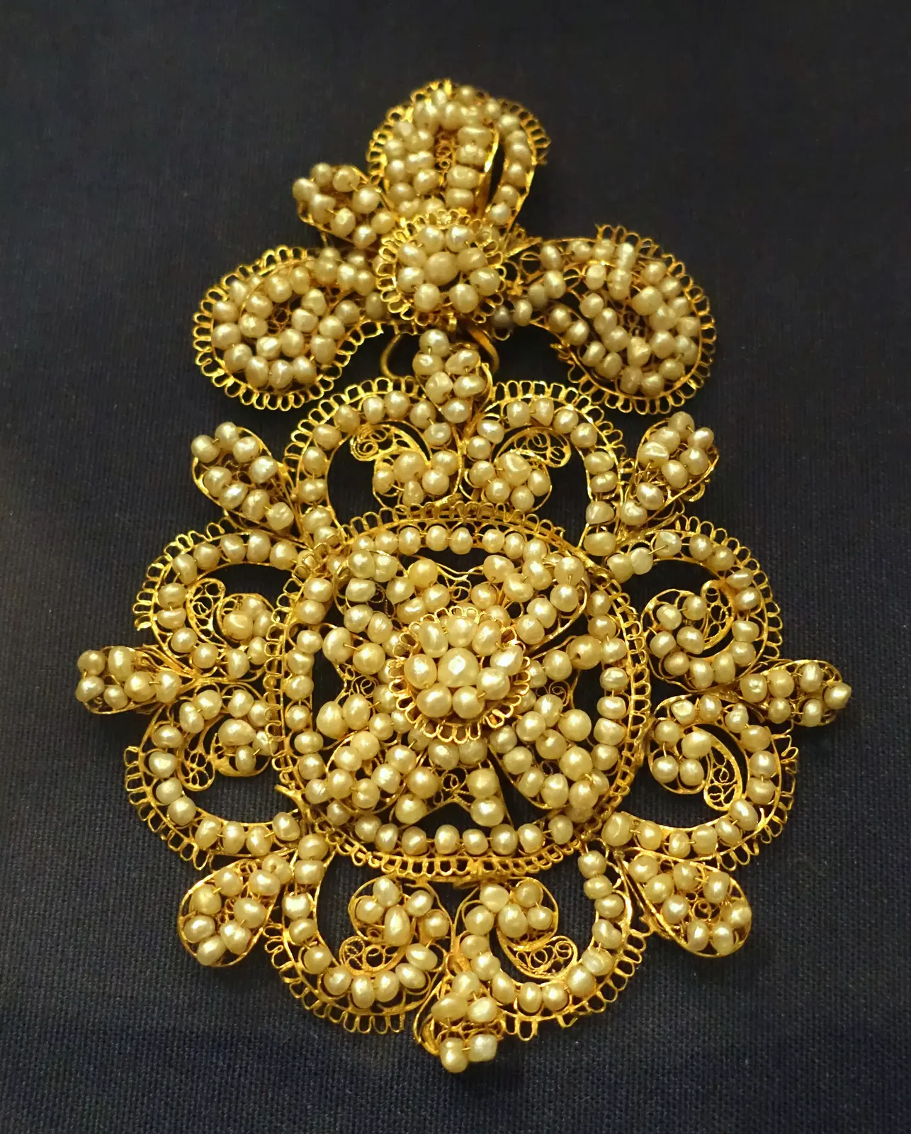 A seventeenth-century rose brooch of gold filigree and red stones, with four baroque pearl drops