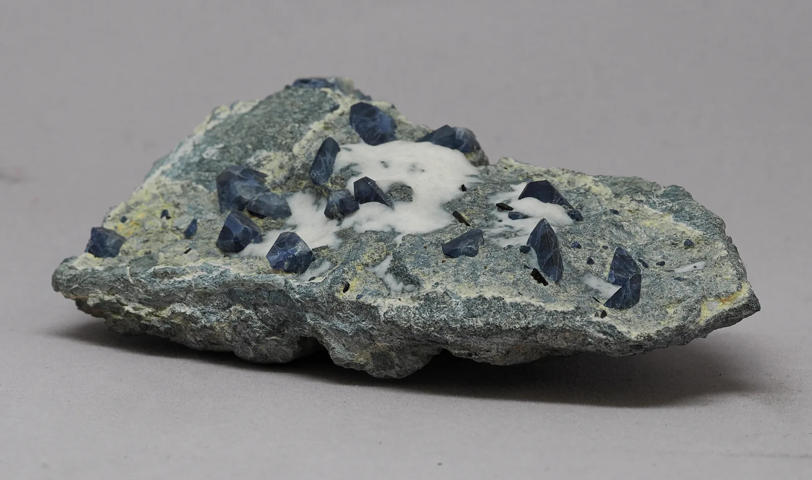 Benitoite and black neptunite crystals in a dark crossite matrix, specimen OM1-203A from the Dallas Gem Mine