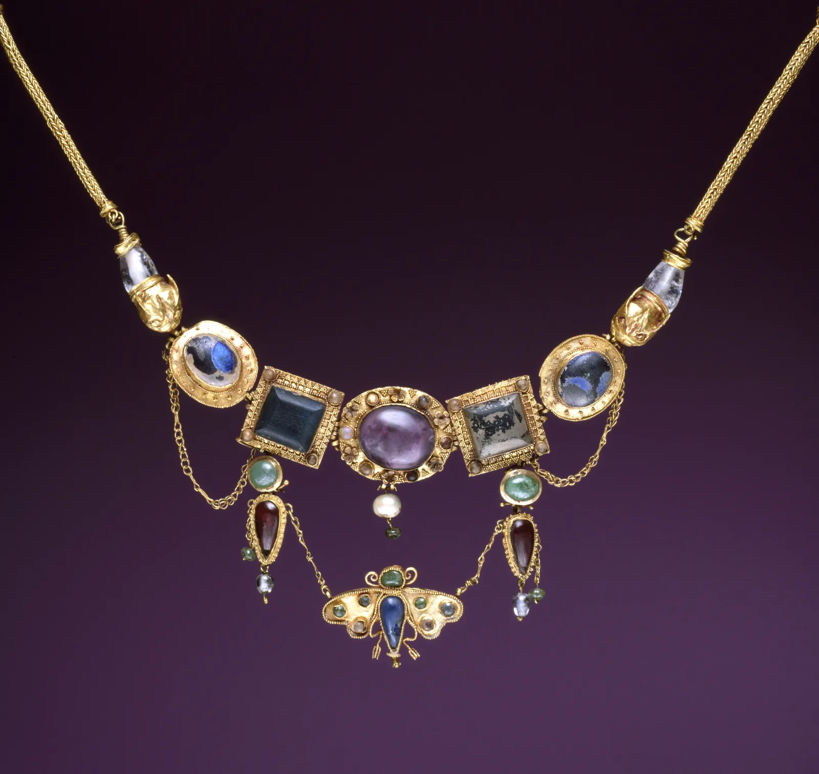 Hellenistic gold necklace with gemstone plaques and a flat butterfly pendant hanging from the center