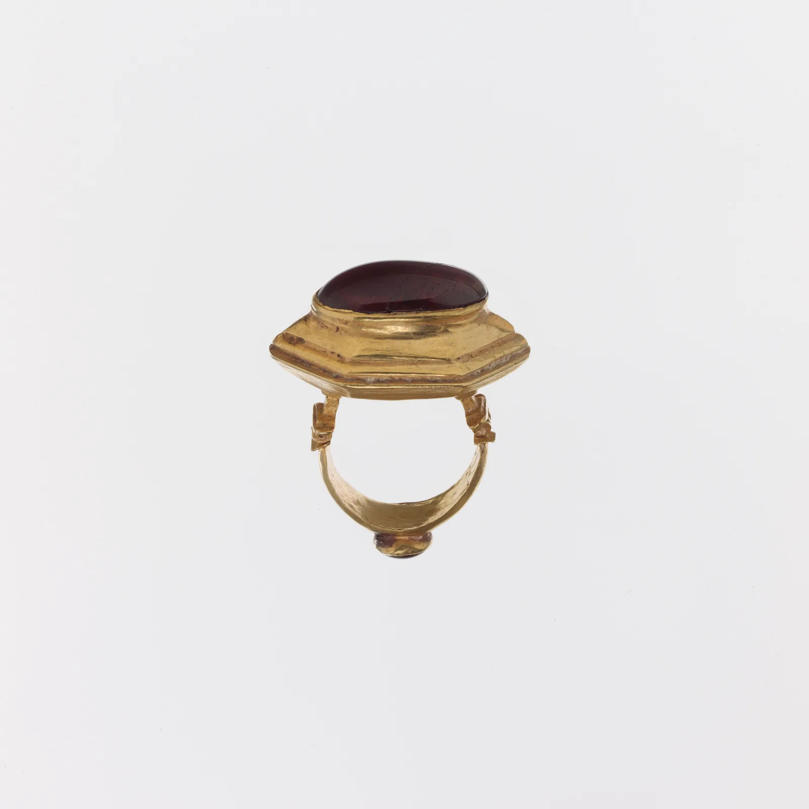 Hellenistic gold ring with a large oval cabochon garnet in a stepped hexagonal bezel
