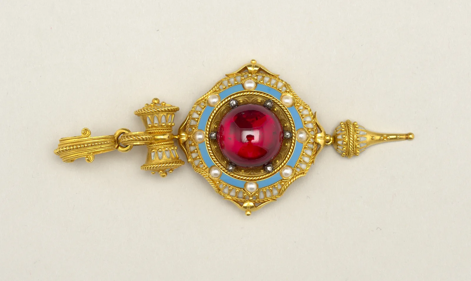Gold lozenge pendant with a circular cabochon carbuncle garnet, blue enamel, pearls, and a pointed drop