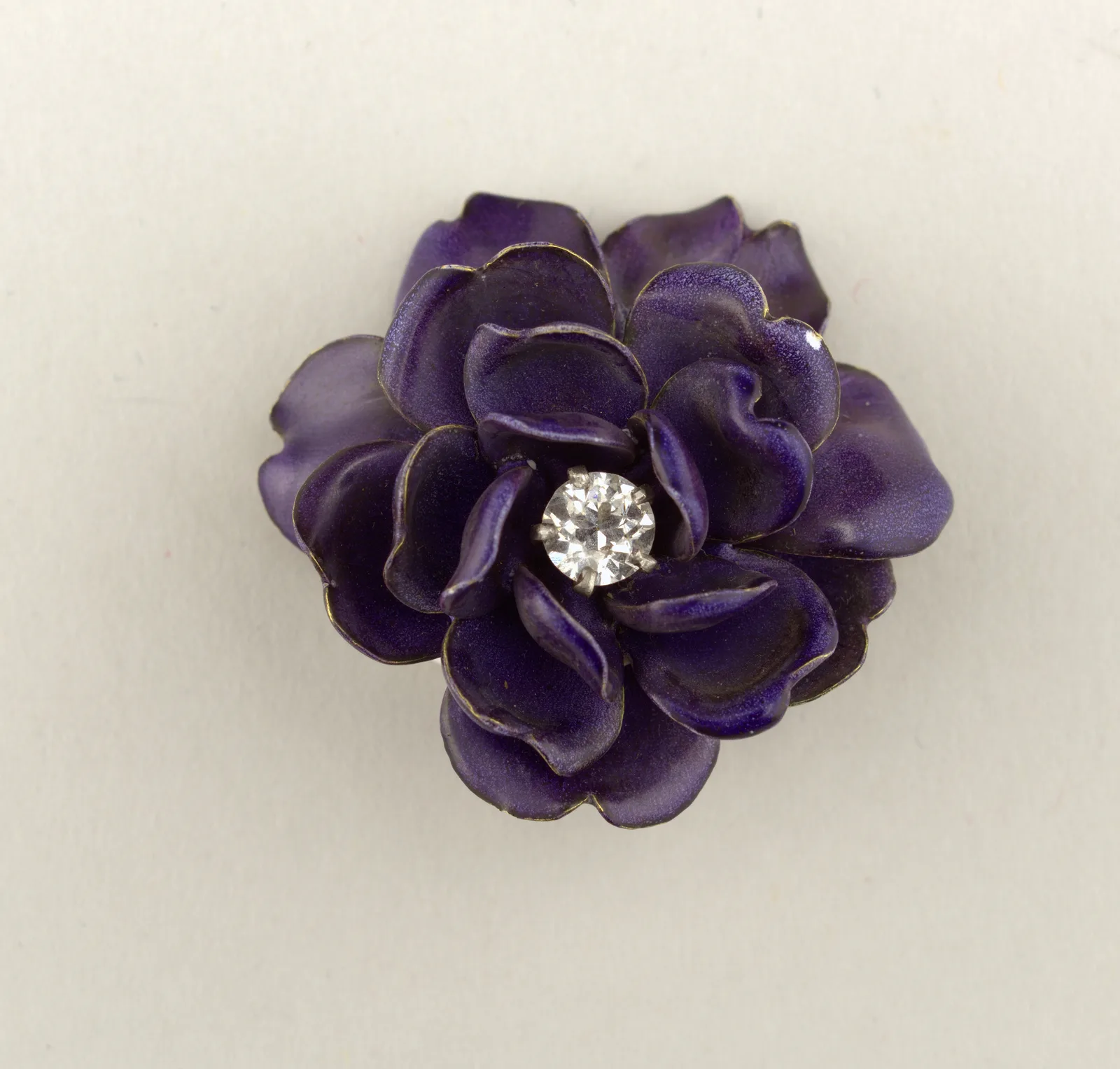 Enamel brooch in the form of a round purple flower with a single diamond at the center and a thin gold outline