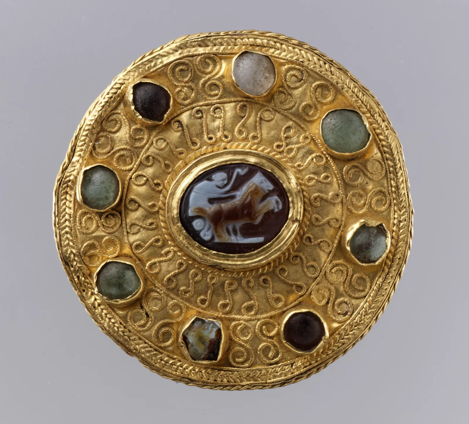 Langobardic gold disk brooch with a Roman onyx cameo of a rider at the center, filigree rings, and a circle of small stones