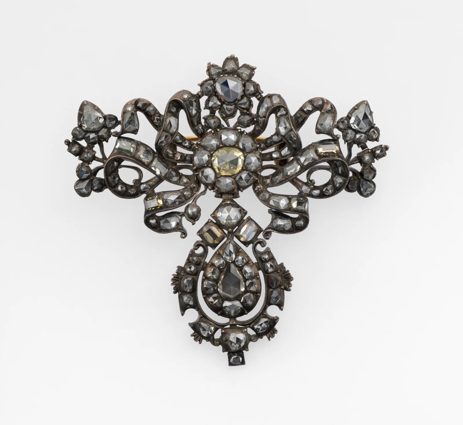 Eighteenth-century silver bow brooch of diamonds, a larger pale center stone, ribbon of smaller stones, and a pear diamond drop of its own weight