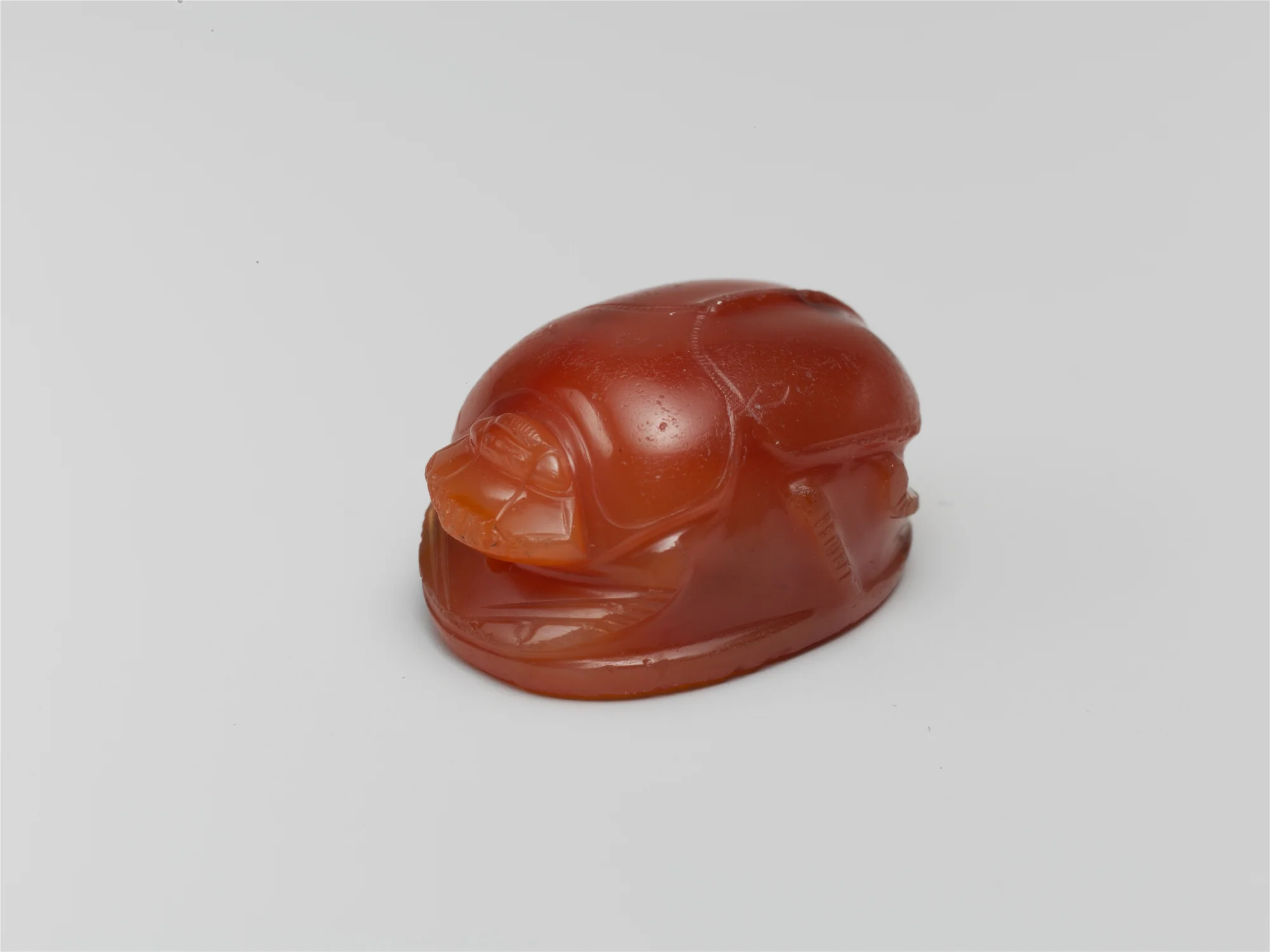 Greek Archaic carnelian scarab carved as a beetle, warm translucent orange, museum catalog still