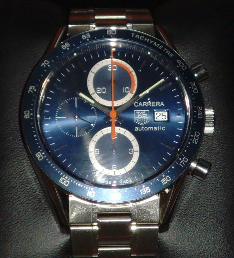 TAG Heuer Carrera automatic chronograph with a blue dial, three subdials, and a tachymeter bezel, shown off the wrist on a white ground