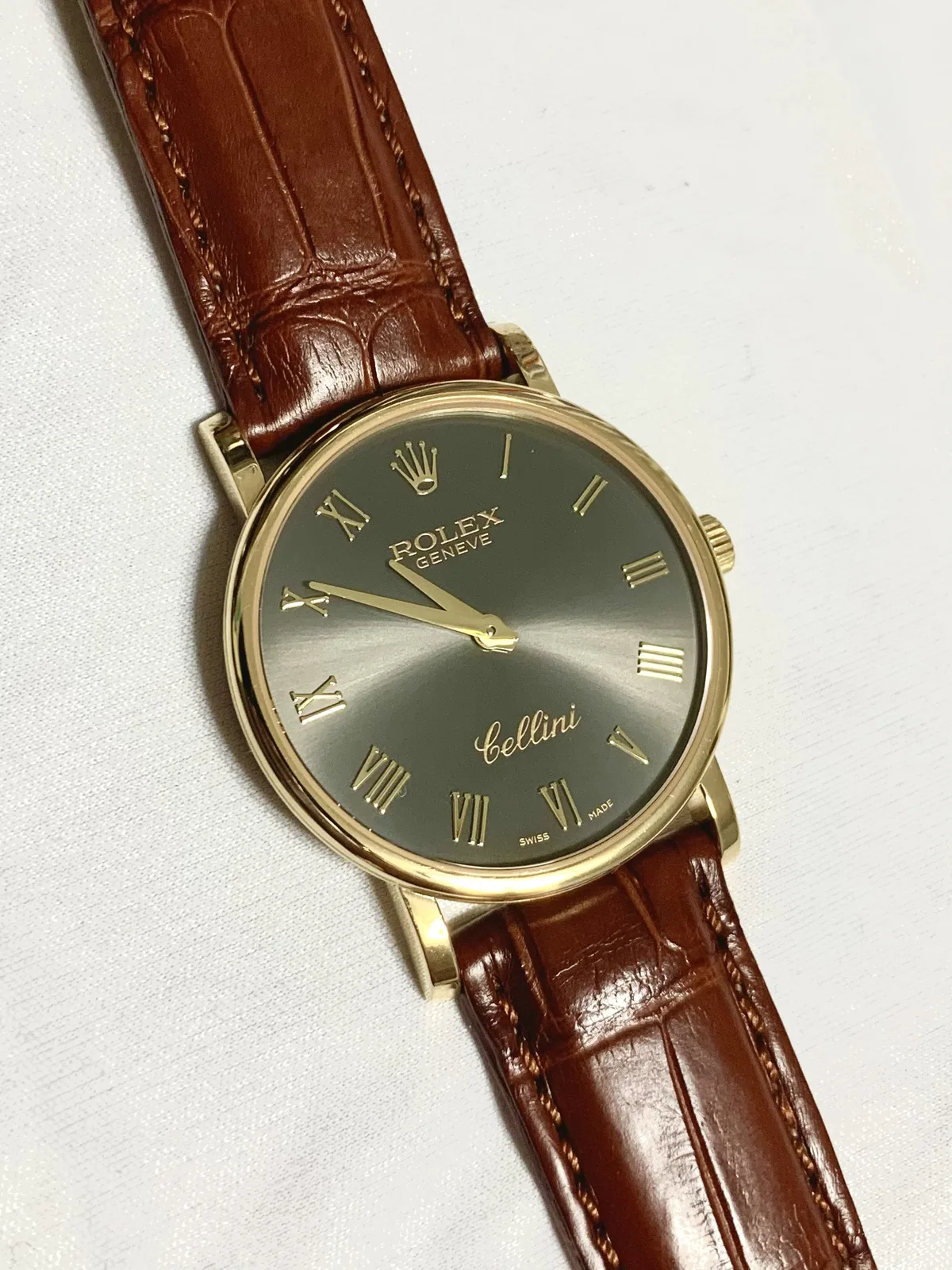 Rolex Cellini reference 5115/8 in yellow gold with a smooth bezel and a warm dial, shown off the wrist on a white ground