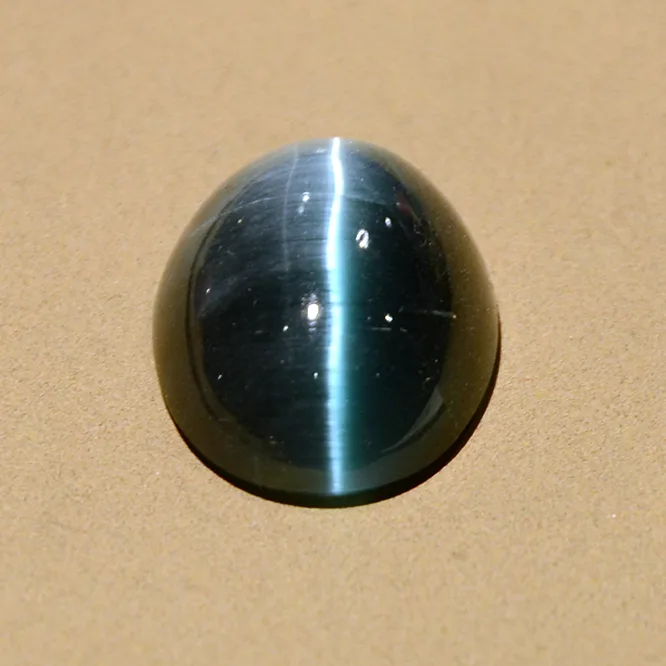 A round green cat’s-eye tourmaline cabochon with a pale band across the dome, a museum stone