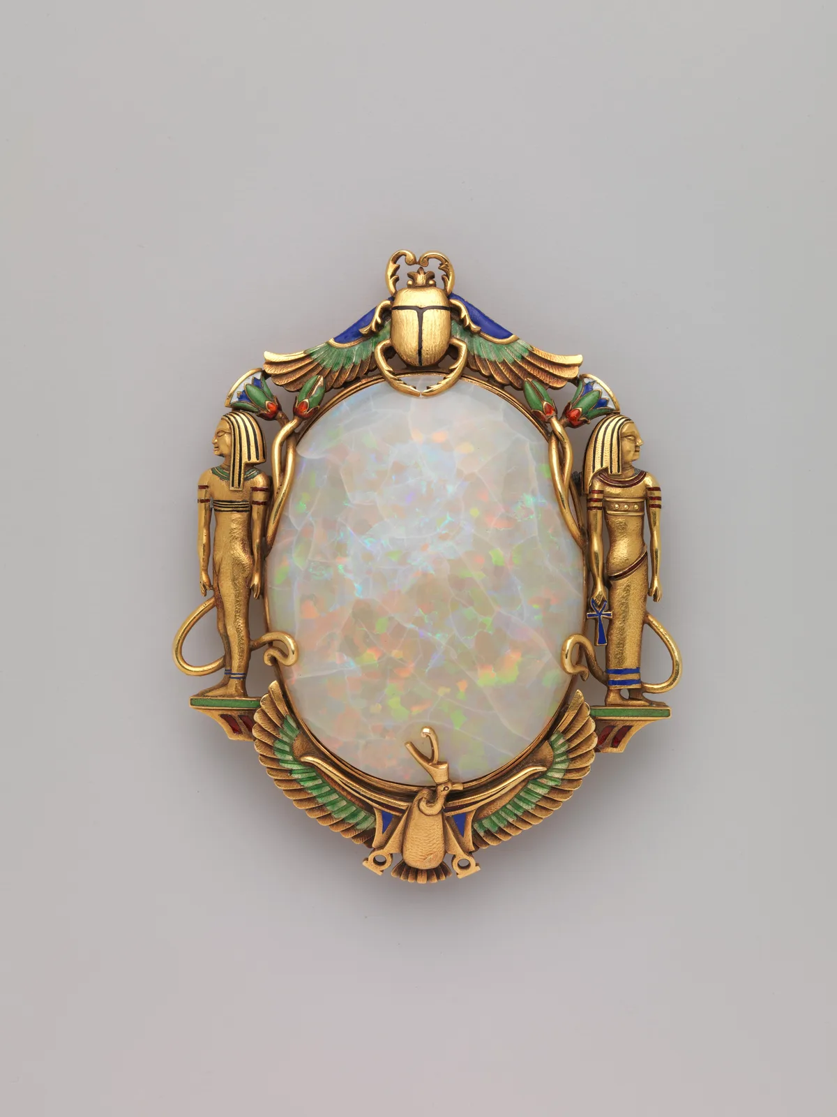 Marcus and Co. gold Egyptian Revival brooch with a large oval opal, enamel scarab, figures, and a winged bird