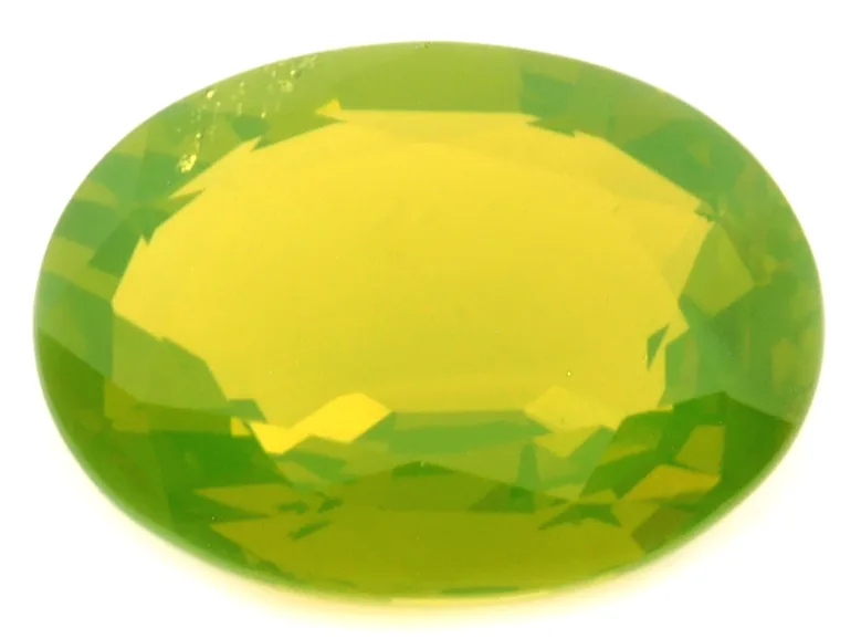 An oval faceted chrysoberyl, yellow-green, on a white ground