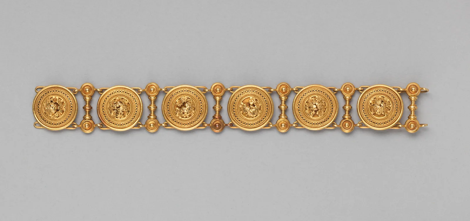 Castellani gold bracelet of six circular granulated medallions joined by vertical bars each finished with three gold spheres like a row of rivets