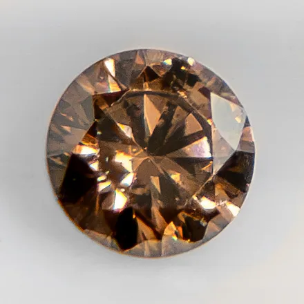 A round brilliant cognac diamond, amber-brown, on a white ground