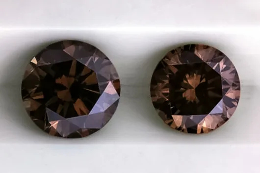 Two darker round brilliant diamonds, chocolate brown, on a white ground