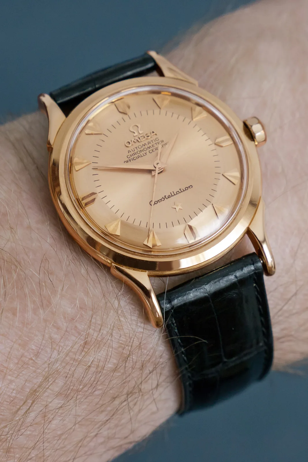 Omega Constellation in rose gold, 1958, with a pie-pan dial, a star at 6, and claws on the bezel, shown off the wrist on a white ground