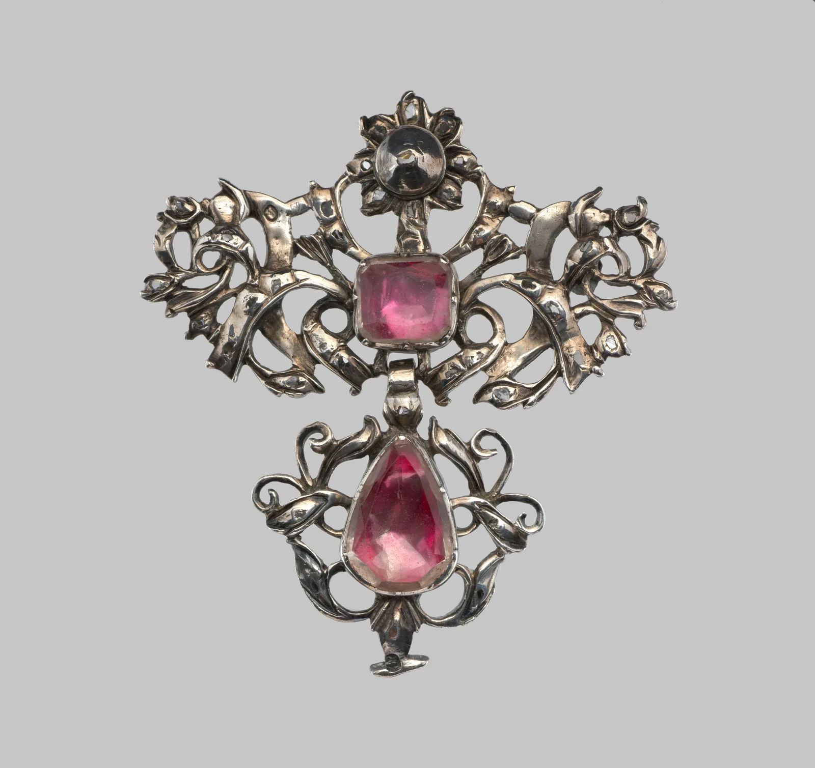 Eighteenth-century silver brooch with a soft square pink jewel at the bow and a pear-shaped pink drop below, openwork leaves around both stones