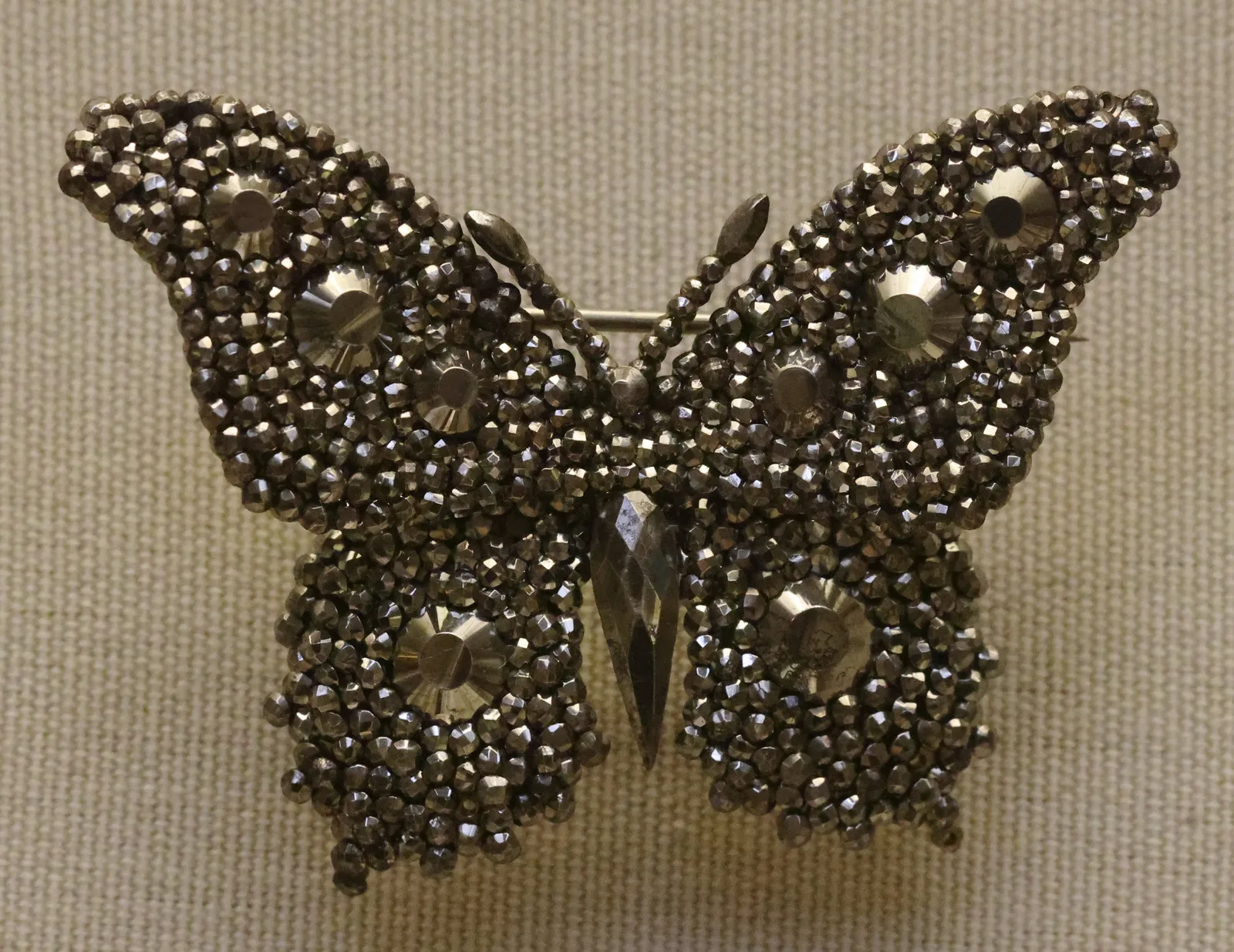 A cut-steel hairpin in the shape of a butterfly, the wings built from faceted steel studs, on a white ground