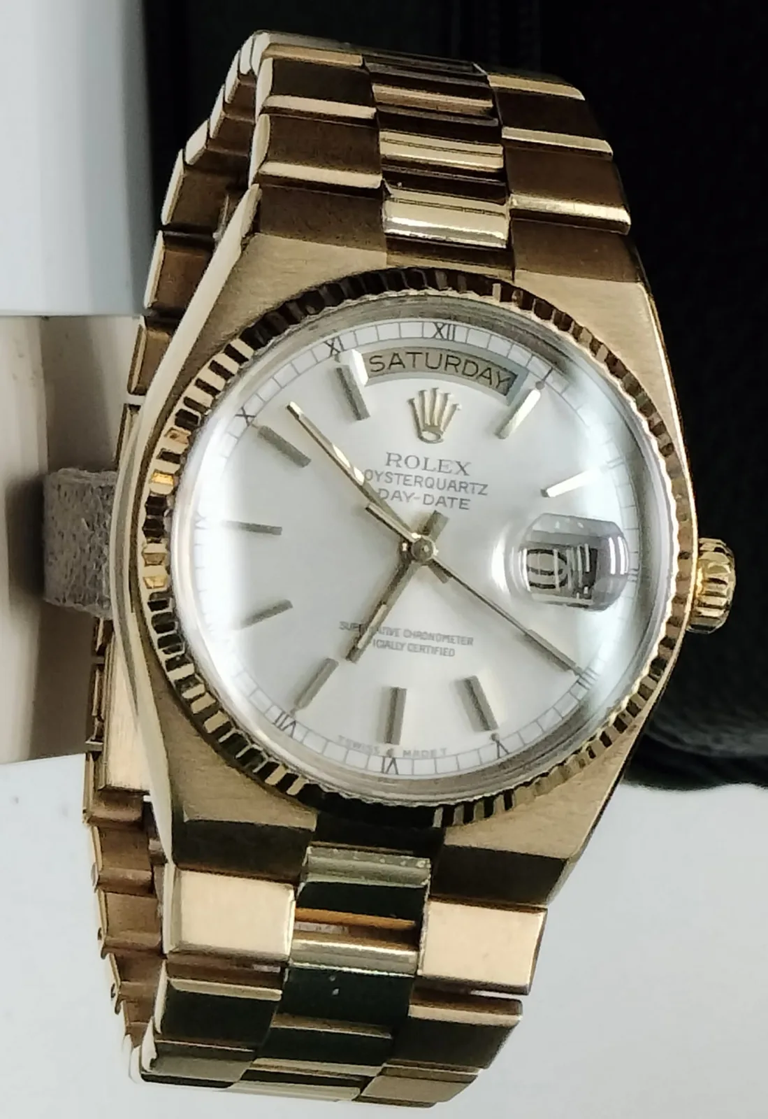 Gold Rolex Oysterquartz Day-Date with an integrated bracelet, a fluted bezel, Sunday in the day window, and a date under the cyclops, shown off the wrist on a stand