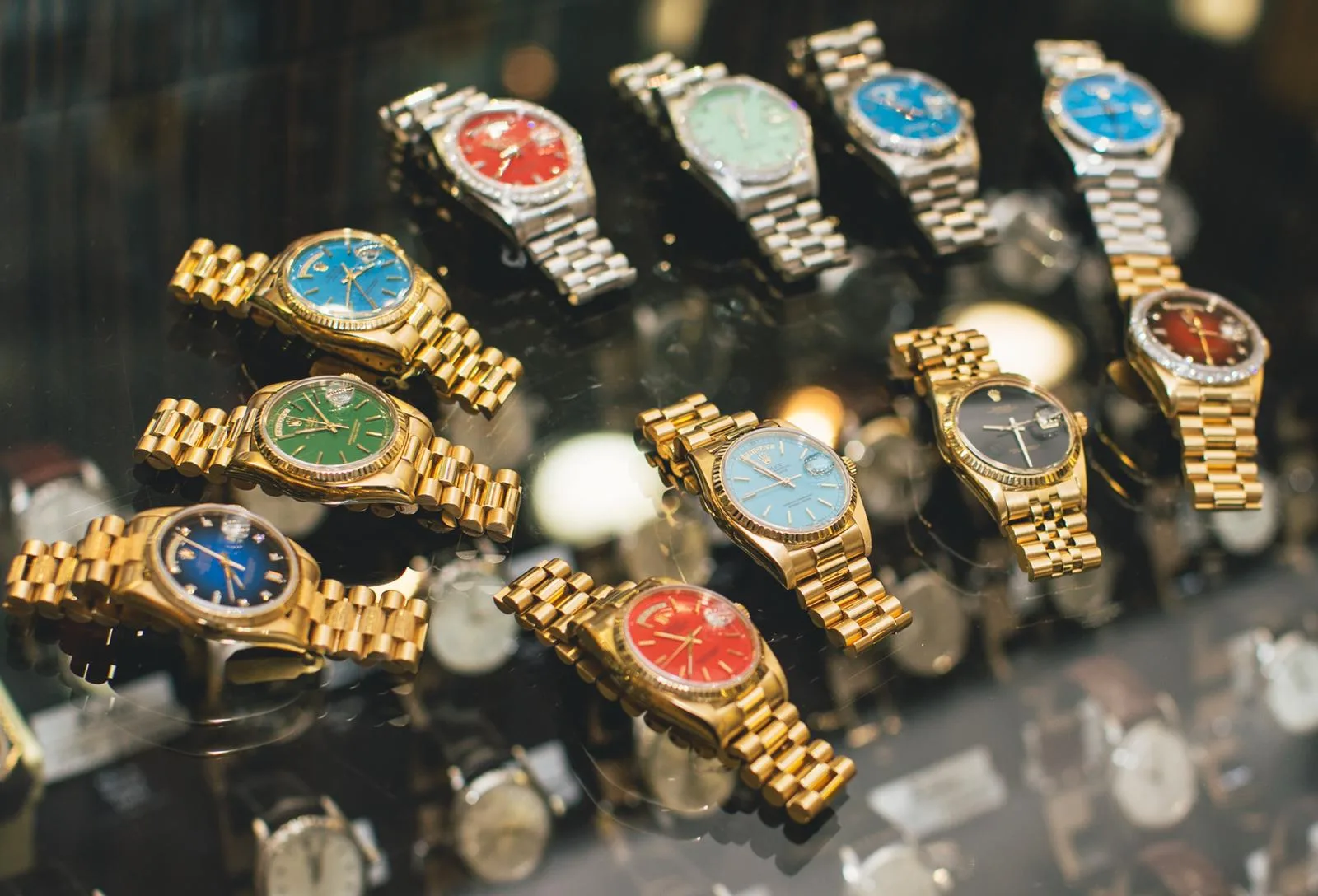 A display of Rolex Day-Date watches with lacquered Stella dials in several colors, day windows and fluted bezels, shown off the wrist
