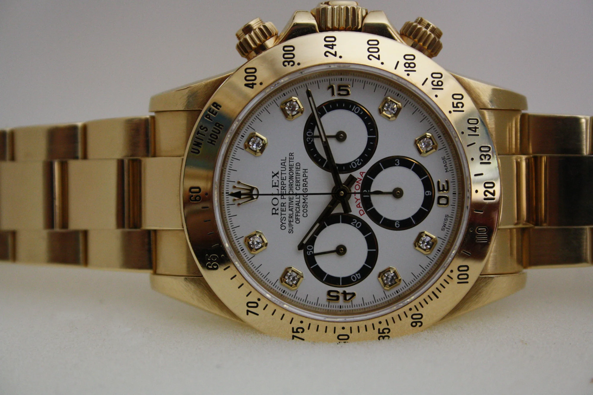 Yellow-gold Rolex Daytona reference 16528 with a white dial, black sub-dials, diamond hour markers, and oyster bracelet, shown off the wrist