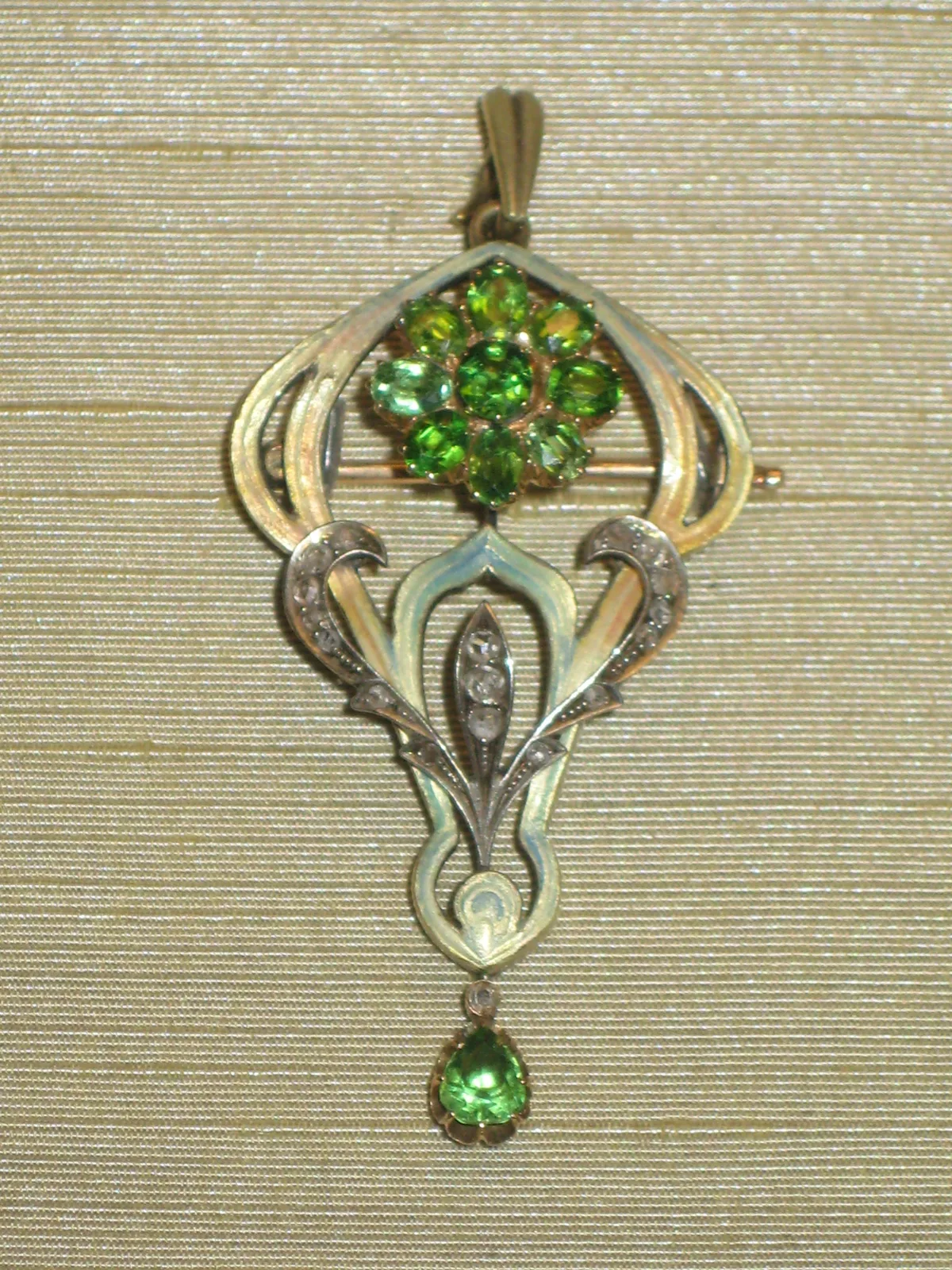 A gold swan brooch-pendant, the body and wings pavé-set with green demantoids, diamonds along the edges, and a pearl drop beneath the tail