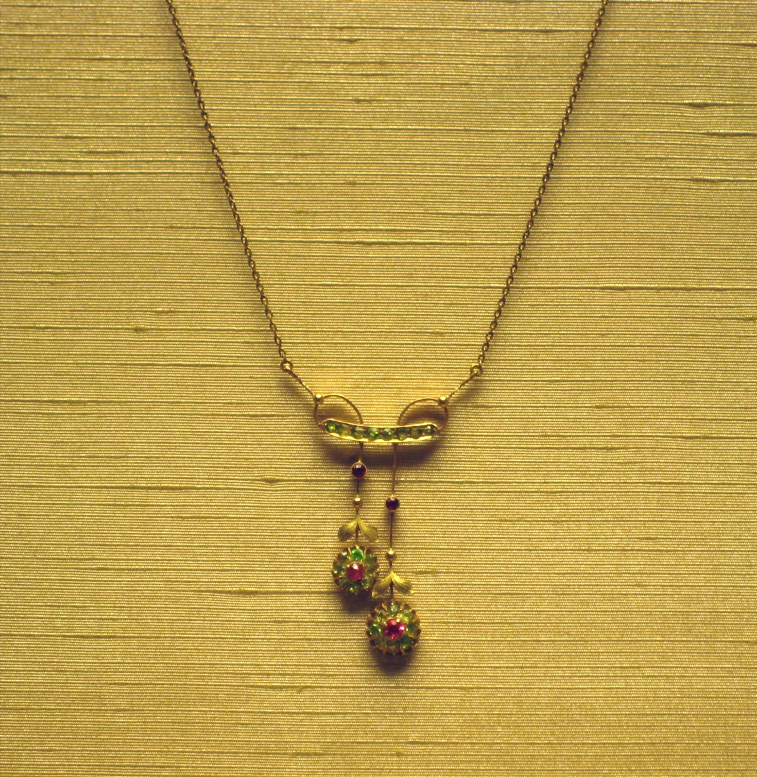 A gold branch pendant with demantoid leaves and a bow at the base, Moscow, 1908–1917