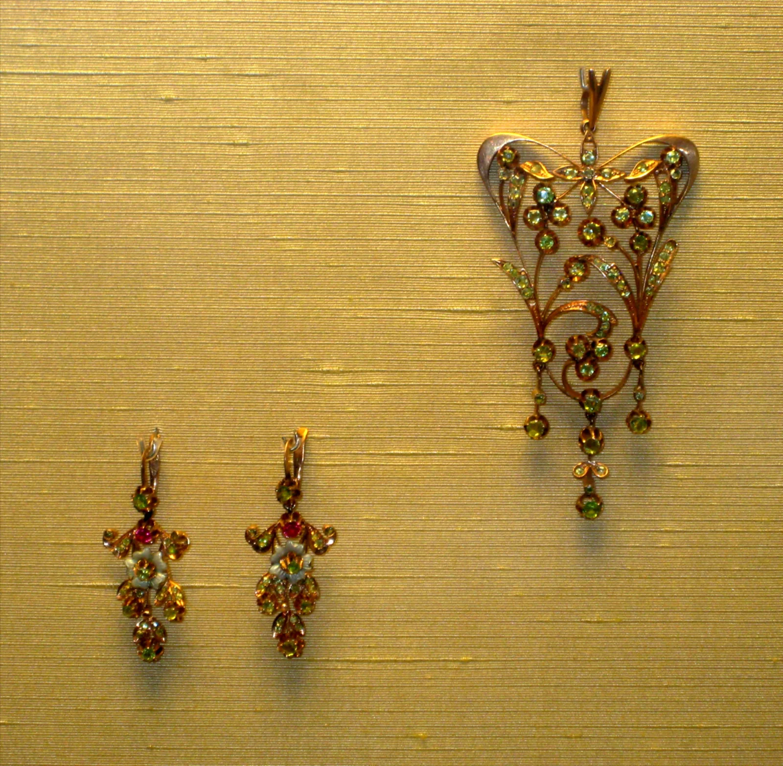 A gold demantoid pendant from the workshop of A. Moskvin, the bow at the top and the leafy spray below