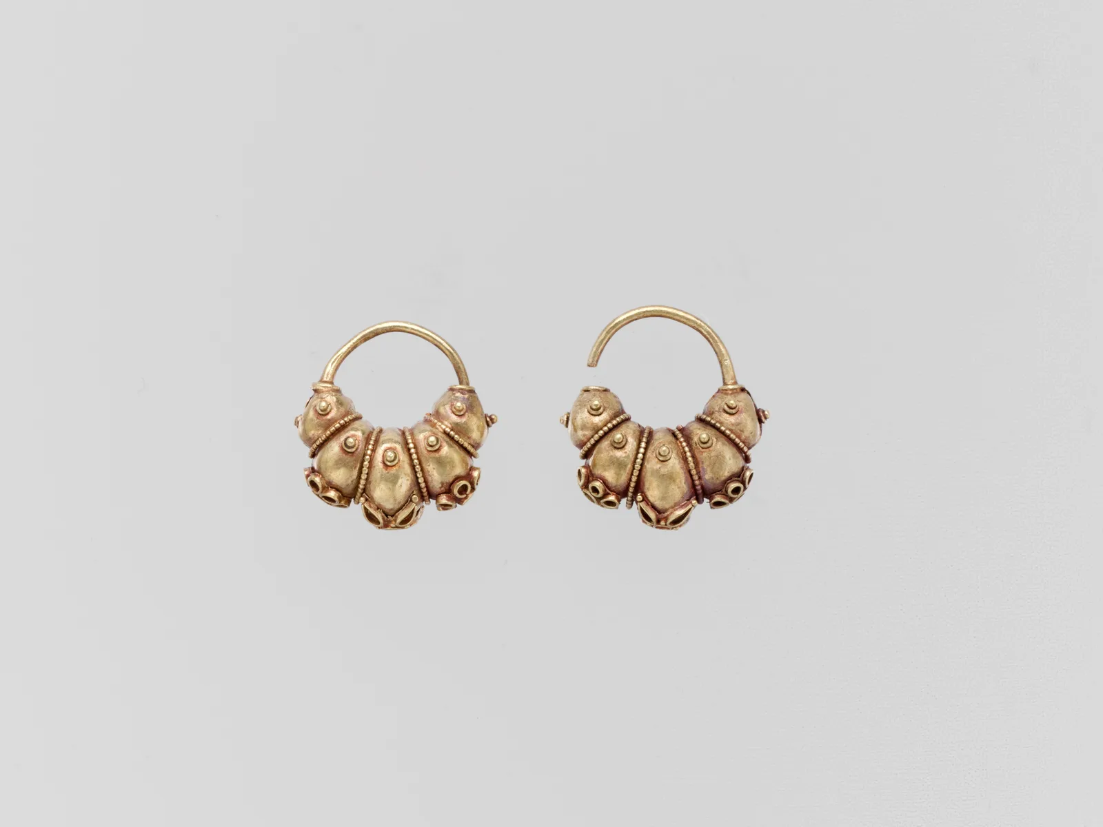 A Cypriot electrum boat earring with lobes and rosettes, the pale gold worked into granules and wire