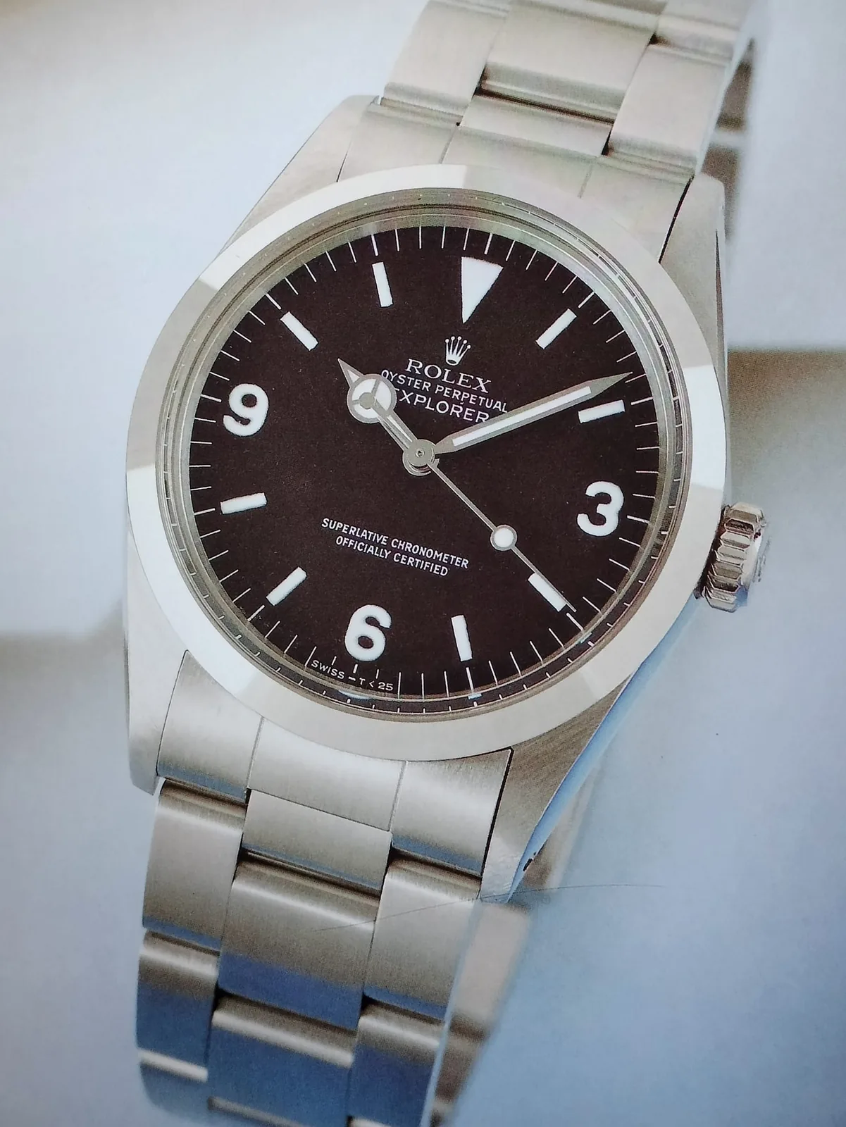 Rolex Explorer reference 1016 with a black dial and numerals at 3, 6, and 9, shown off the wrist on a white ground