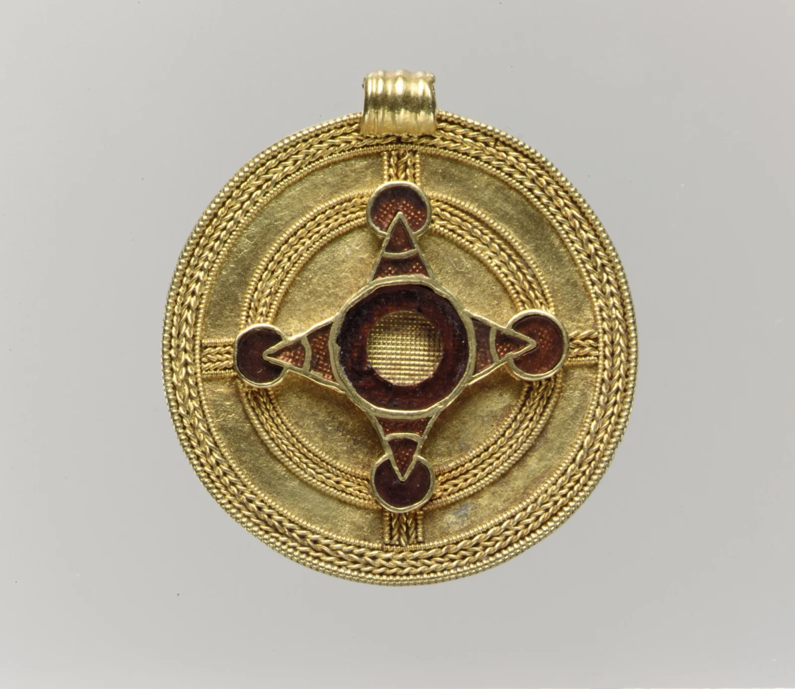 Anglo-Saxon gold pendant with a garnet cloisonné cross, waffle-patterned foil visible through the stones, and a twisted-wire border