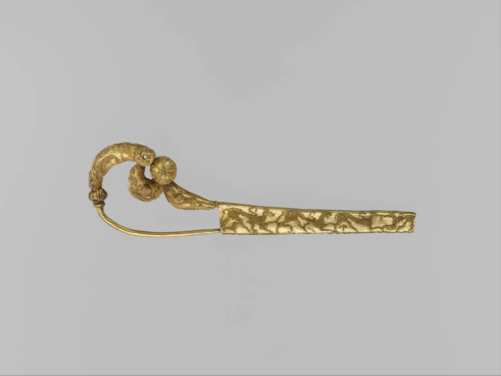 An Etruscan gold serpentine fibula whose bow is covered with birds in granulation