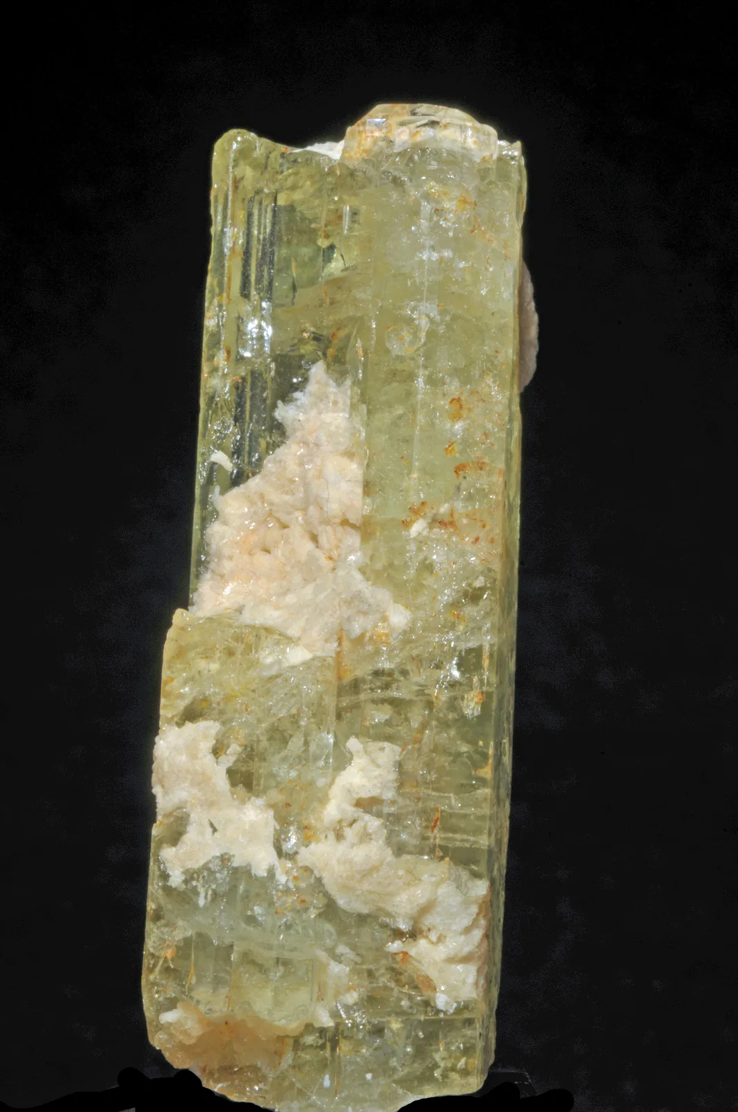 A single golden-yellow heliodor prism with long faces, a crystal from Araçuaí on a pale ground