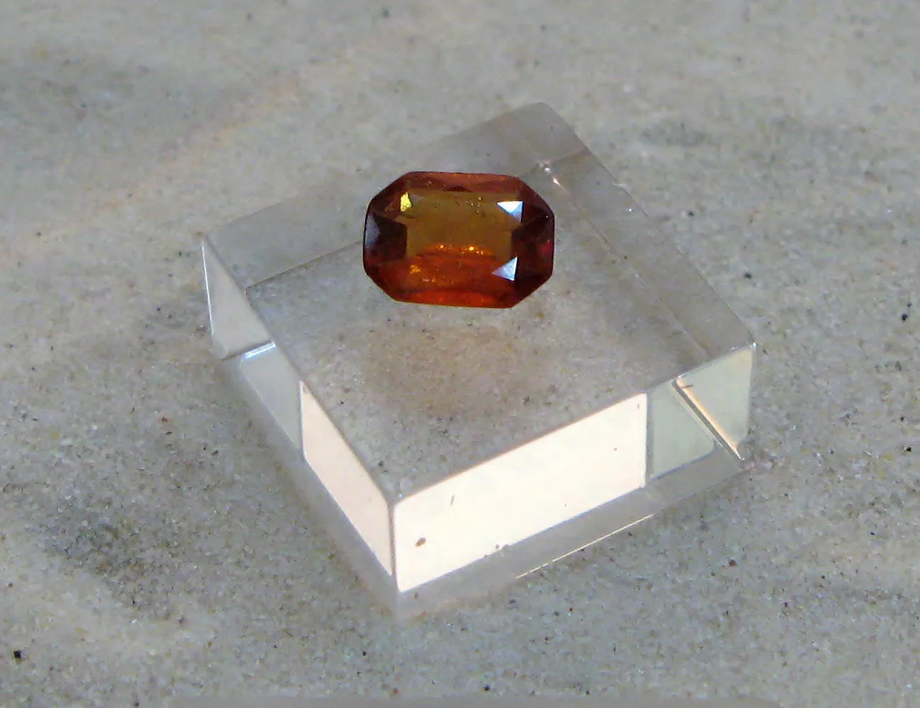 A faceted hessonite of cinnamon orange-brown, table cut, on a white ground