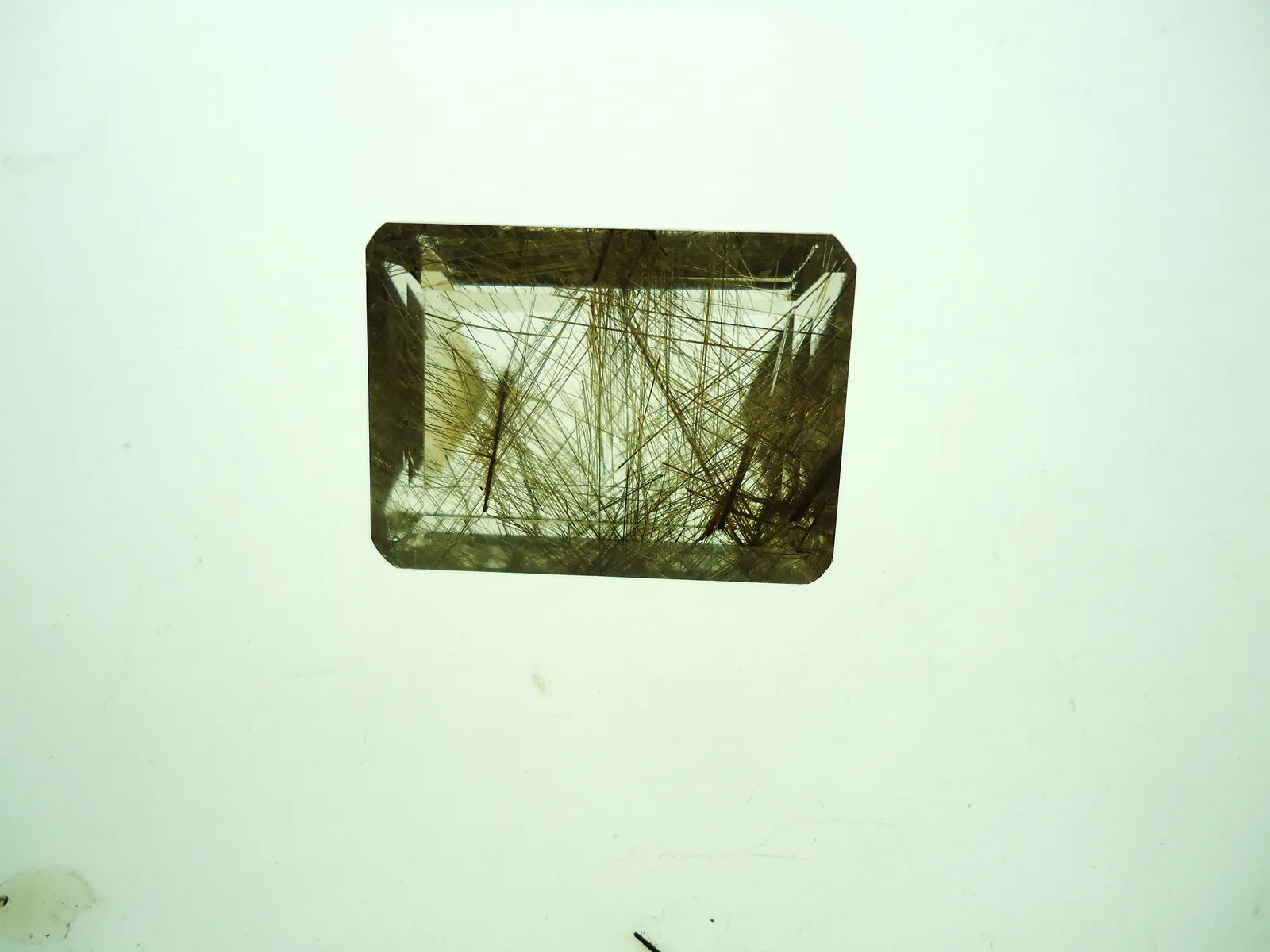 A clear quartz crystal shot through with fine golden rutile needles
