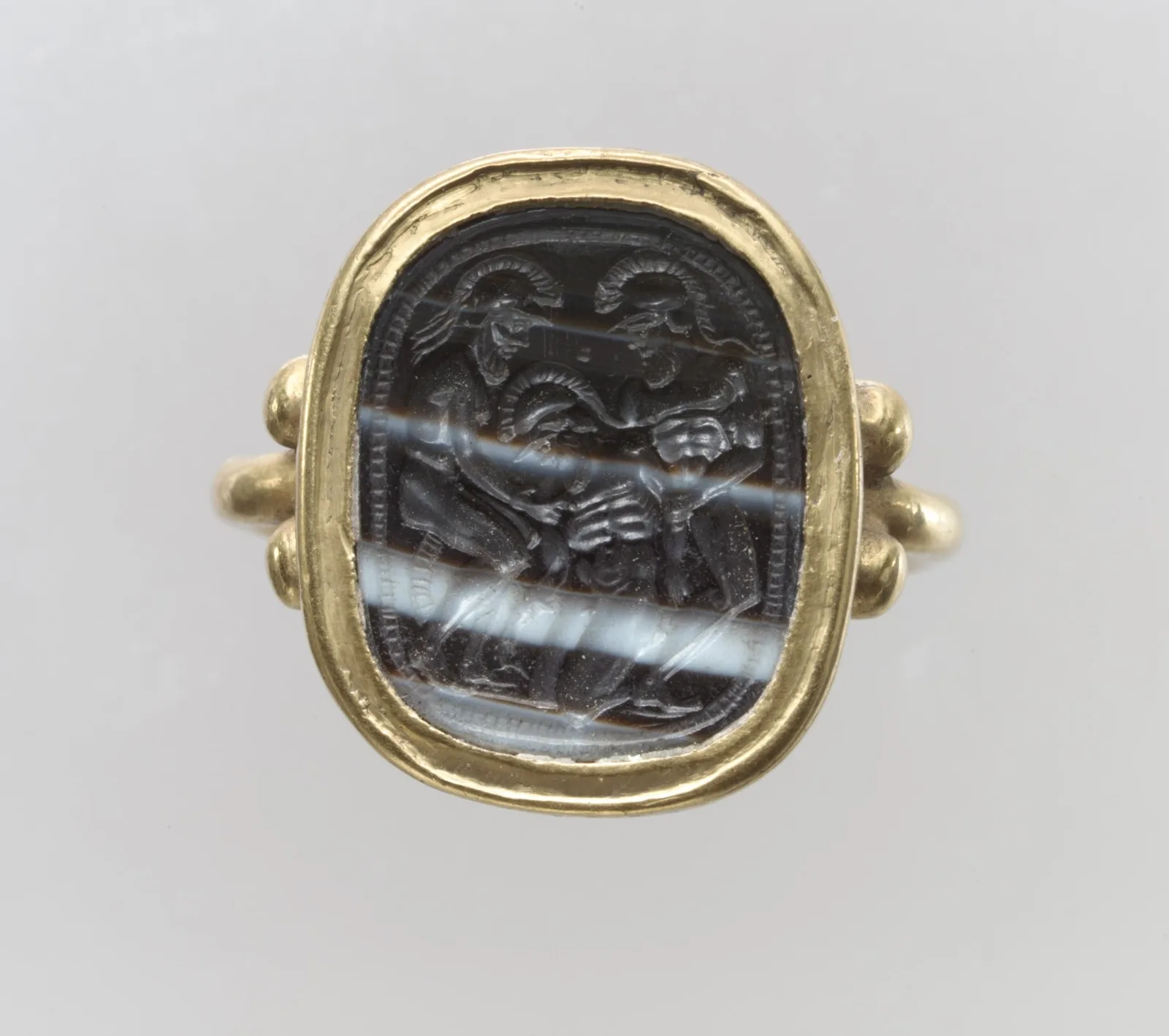 Langobardic gold finger ring set with an Etruscan banded-agate intaglio, the carved face recessed in the stone
