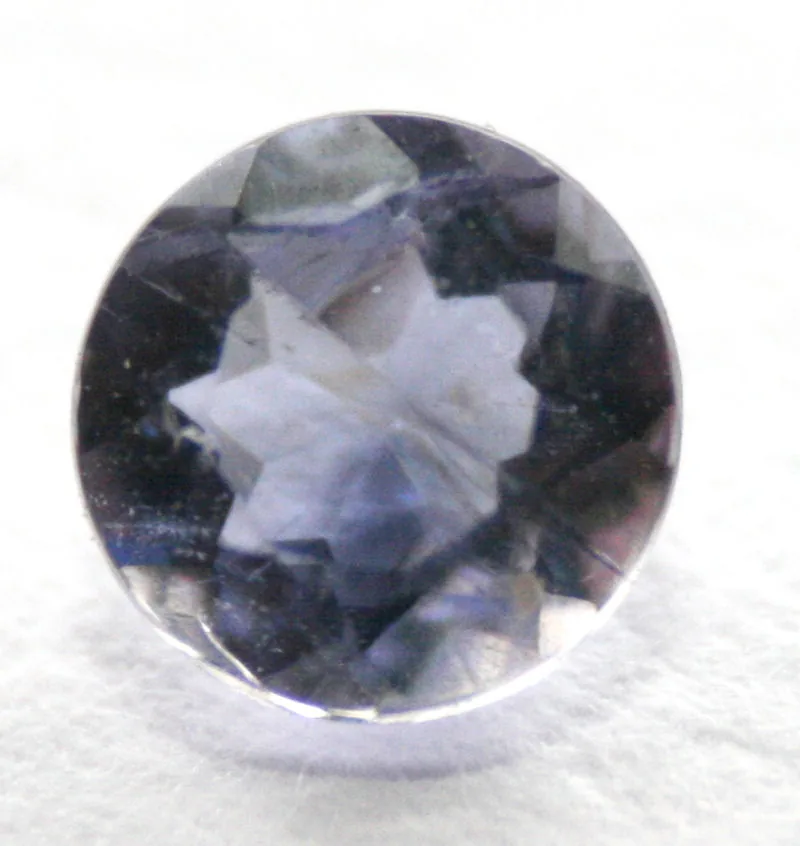 Faceted iolite gemstone, a cool violet-blue brilliant on a white ground