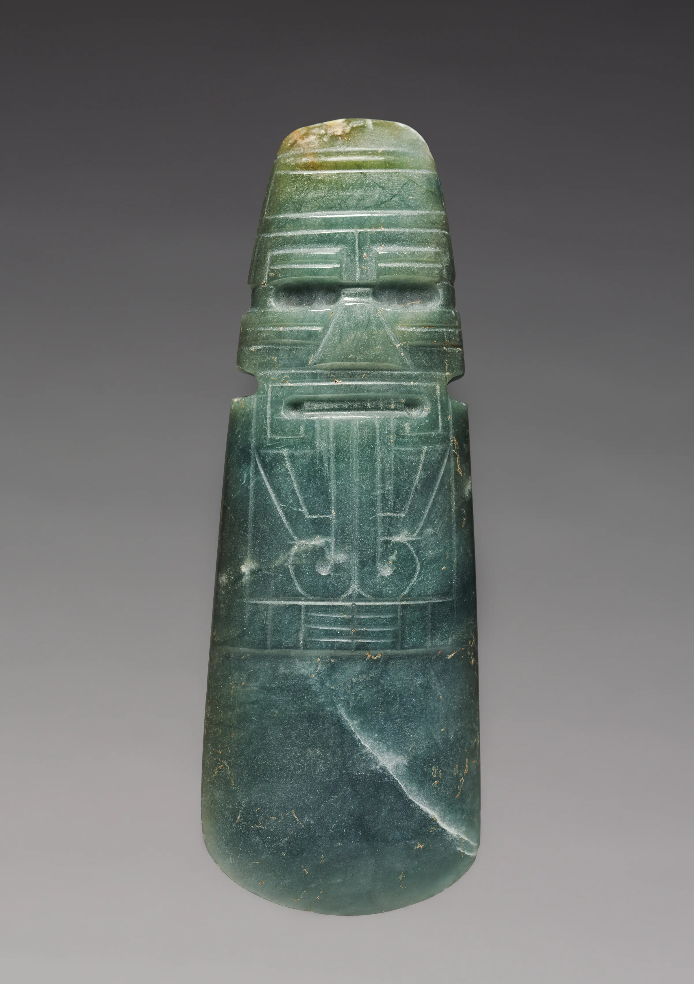 Costa Rican jadeite celt pendant carved as a stylized face above a smooth dark-green blade