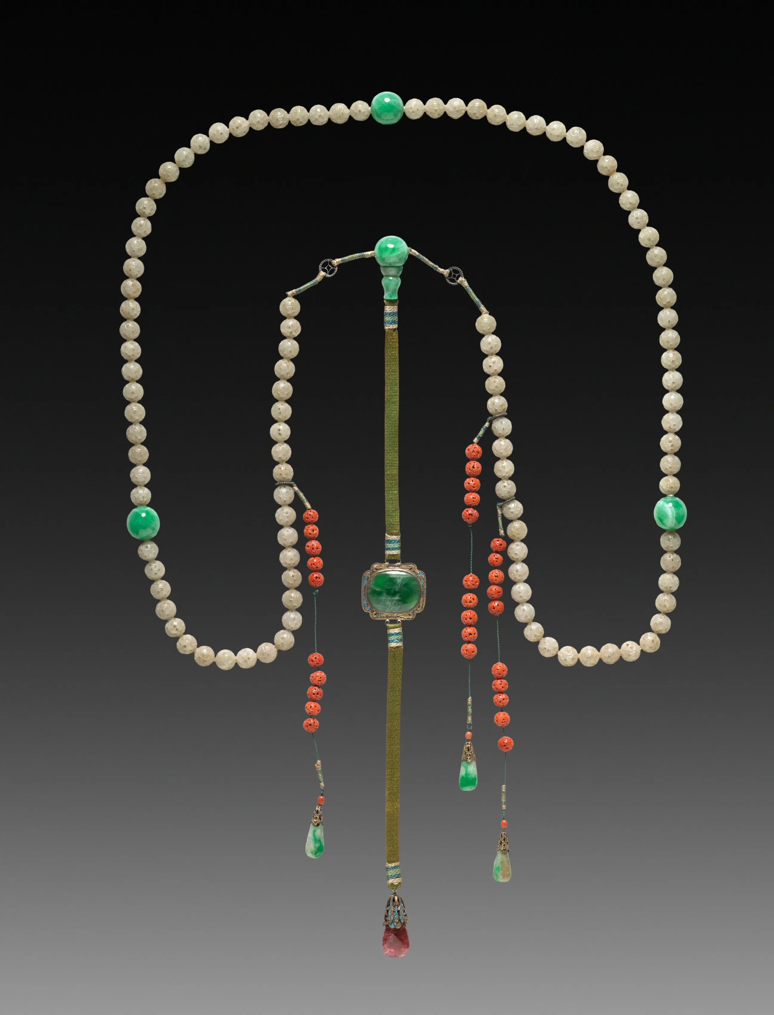 Qing mandarin necklace of pale jade beads with three green jade pauses, a square green jade plaque, and coral-bead side drops
