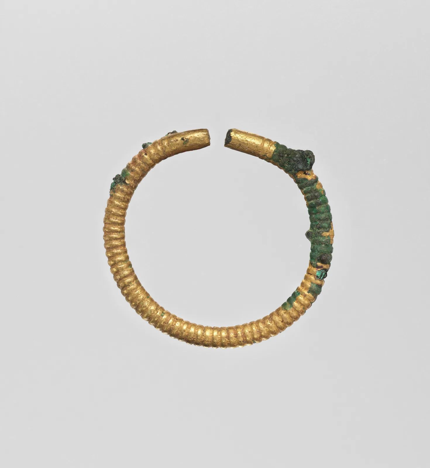 Ptolemaic gold bangle formed as an open ribbed hoop with two blunt terminals almost meeting