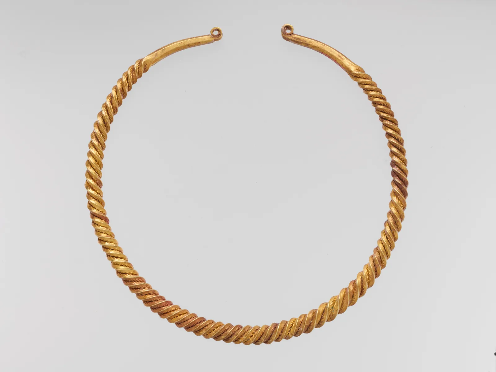 Celtic gold neck ring of twisted metal with two smooth terminals ending in small loops