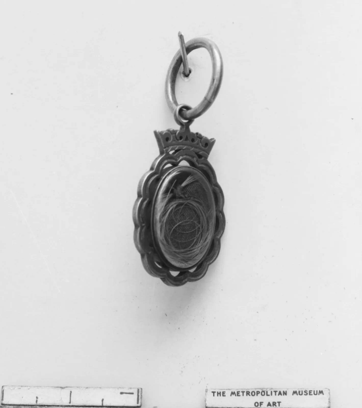 British silver-gilt locket opened to an oval compartment of braided hair under glass, with a hinge and a loop at the top