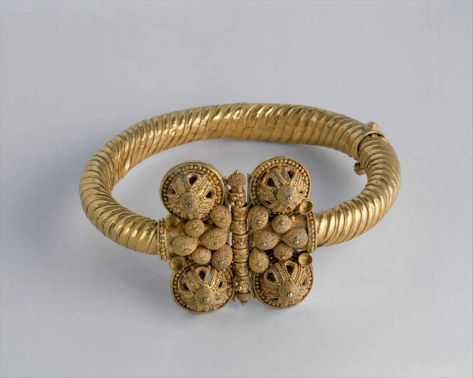 Eleventh-century gold armlet with a twisted hoop and a large hinged clasp of four granulated lobes