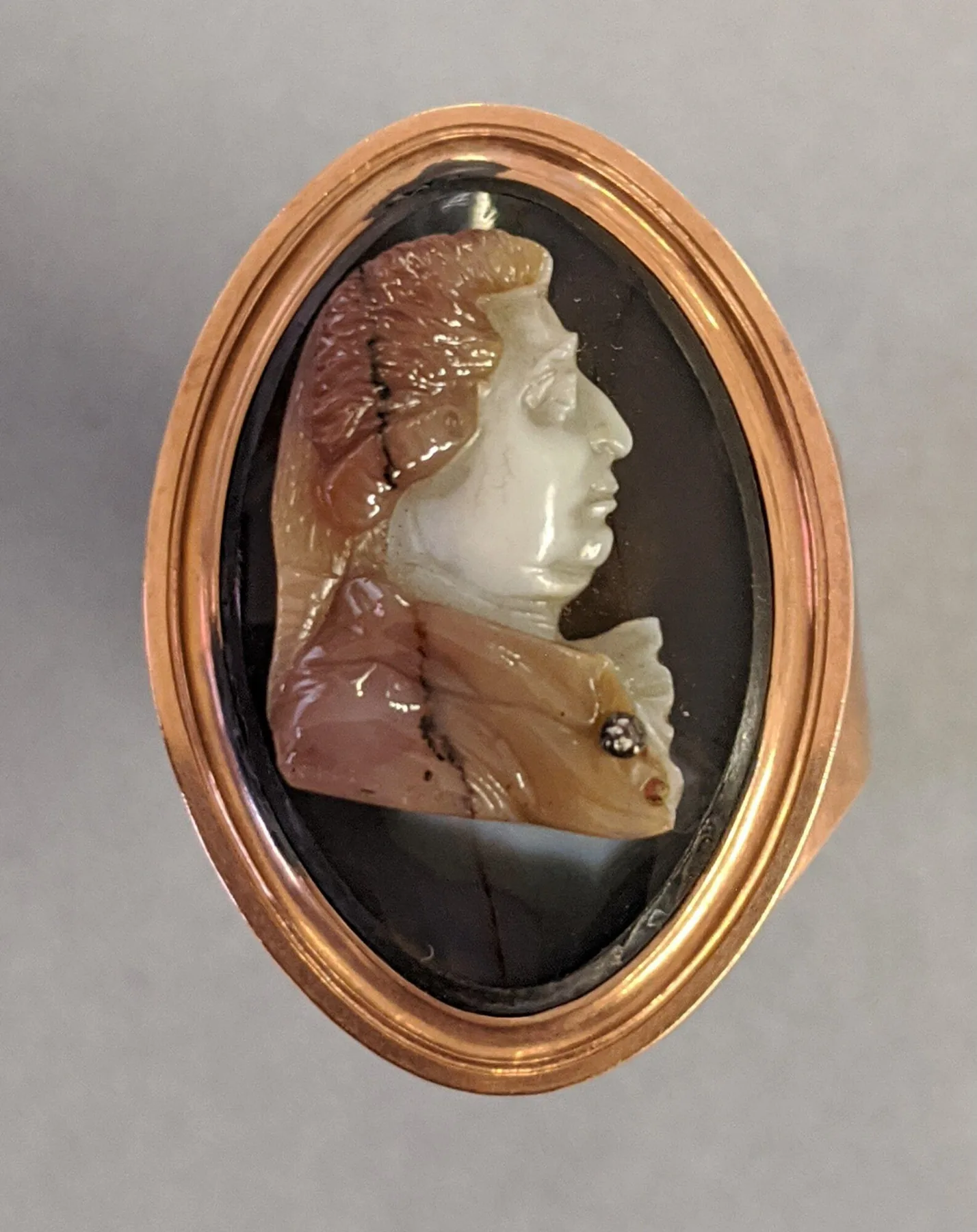 Gold ring with a marquise-shaped bezel holding an onyx cameo bust, the boat outline pointed at both ends
