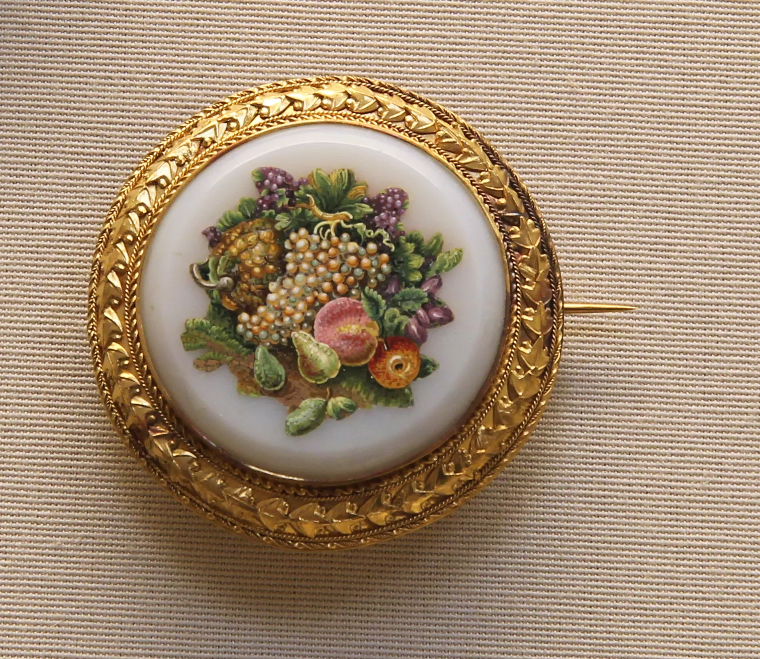 A gold brooch with a micromosaic of fruit in a white opaline glass surround, British Museum
