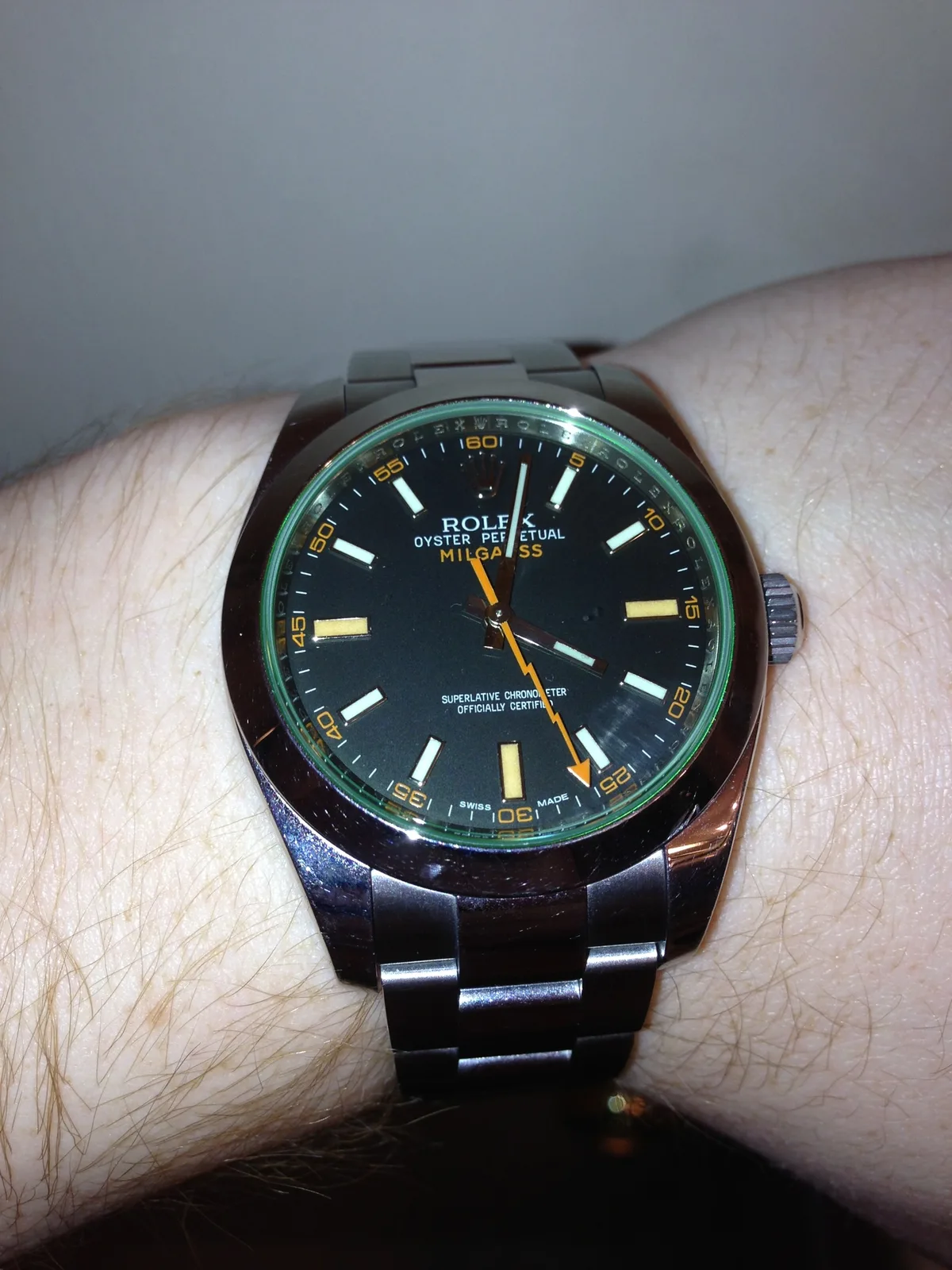 Rolex Milgauss GV with a black dial, an orange lightning seconds hand, and a green sapphire crystal, shown off the wrist